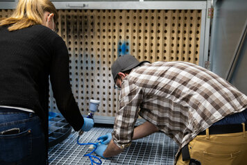 Agnes und Lukas lackieren das Holz mit blauer Farbe